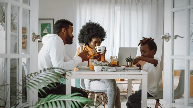 Customer engagements platform Image- A husband, wife, and child are seated at a table, as they look at a laptop together.