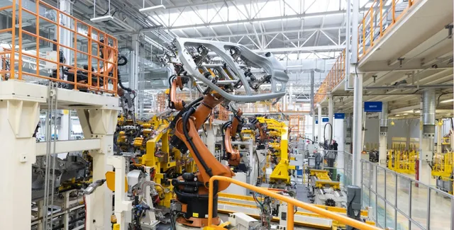 Robotic welding arms working on a metal pipe in an industrial workshop